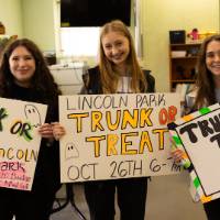 Students holding Trunk or Treat signs